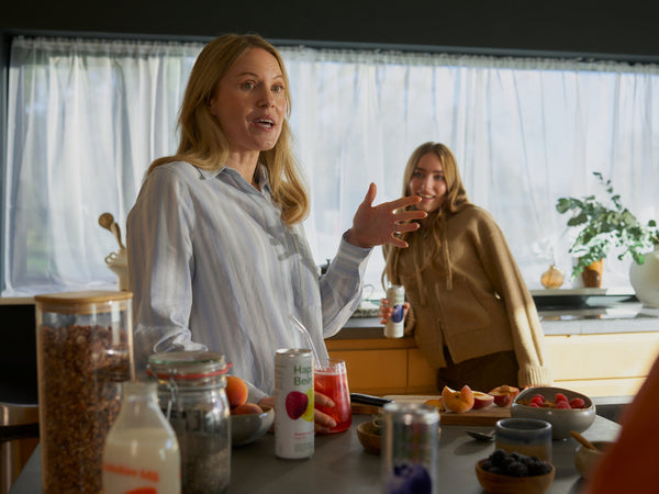 Two women enjoying Happy Being White Tea with a healthy breakfast in a bright kitchen, highlighting a simple daily wellness ritual.