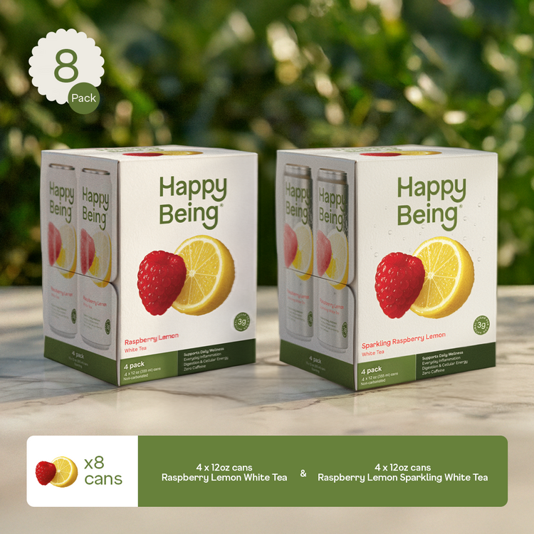 Two boxes of Happy Being sparkling white tea with raspberry and lemon on a wooden surface with greenery in the background.