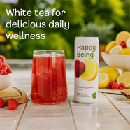 Happy Being Raspberry Lemon White Tea served over ice beside a can, with fresh raspberries and lemons highlighting daily wellness ingredients.